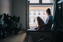 Girl Sits On Windowsill Of Berlin Apartment In Summer