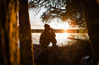 © Aimee Bartee/Stocksy - Woman Sitting on Rock at Sunset with a Drink