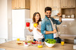 © Sanja - Young good-looking Caucasian husband and wife having fun and dancing while they are preparing a healthy meal in the kitchen.