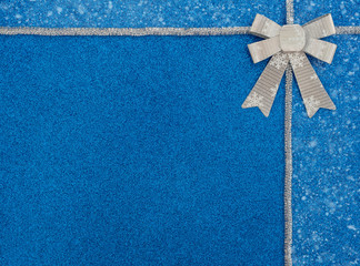 Christmas or winter blue background with snow, silver tinsel and bow with white snowflakes. New Year greeting card. Xmas , New Year or winter concept. Flat lay style with copy space.