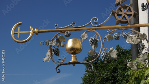 Medieval guild sign for a restaurant and wine cellar showing a golden wine goblet surrounded by wine leaves Poster Mural XXL