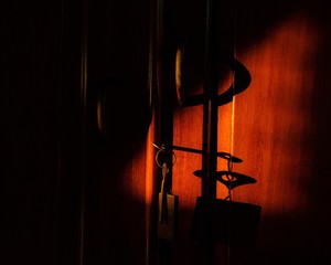 Poster - Closeup of keys in a locker of a wooden door under red lights and shadows