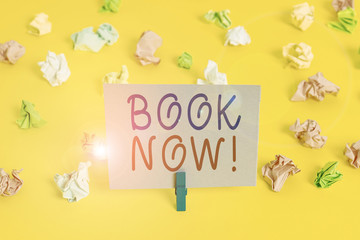 Conceptual hand writing showing Book Now. Concept meaning guaranteed to have place because you have already purchased it Colored crumpled paper empty reminder white floor clothespin