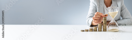 Fotografía Businesswoman With Hourglass And Stack Of Coins