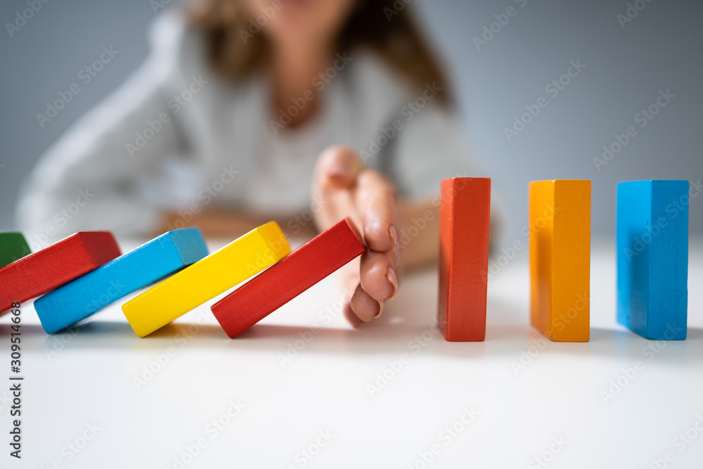 Businessperson Hand Stopping Colorful Blocks From Falling - obrazy, fototapety, plakaty 