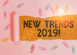 Conceptual hand writing showing New Trends 2019. Concept meaning general direction in which something is developing Paper clip and torn cardboard on wood classic table backdrop