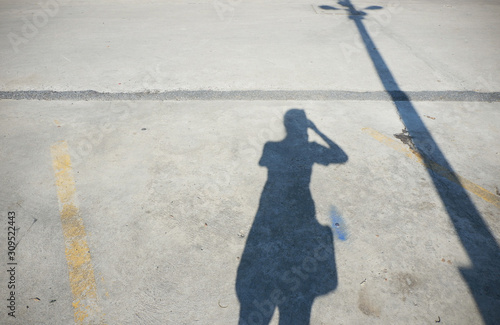 Shadow people on the concrete floor with electric pole background, Shadow of a woman while taking photo background, woman shadow on the parking lot floor under the sun