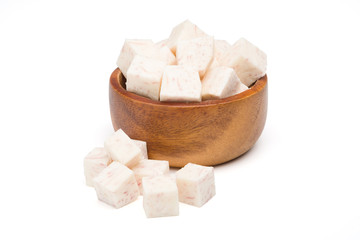 Diced taro root in wooden bowl on a white background with clipping path.