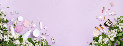 Natural woman make up cosmetics with spring white lilac bloom. Top view. Spring female decorative cosmetics on purple background. Organic cosmetic for make up banner. Cosmetic and brushes in blossom