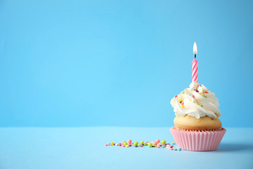 Delicious birthday cupcake with candle on light blue background. Space for text