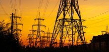 Electricity Pylons Bearing The Power Supply Across A Rural Landscape During Sunset. Selective Focus.