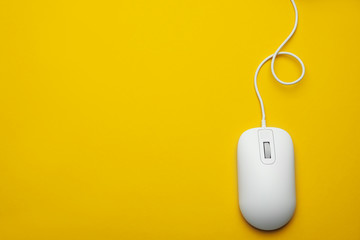wired computer mouse on yellow background, top view. space for text