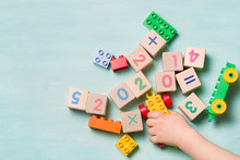 Little Cute Toddler Boy Playing With Colorful Cubes And Bricks On A Turquoise Table. Top View On Wooden Cubes With Numbers Of The Year 2020. Educational Games For Children And Early Development.