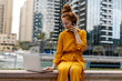 © PinkCoffee Studio - Young Woman sitting in Dubai Marina aria, talking on the phone and work on laptop. Student or  freelancer lifestyle.