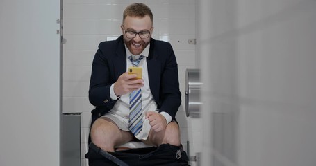 Businessman reading message in restroom.