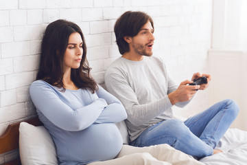 Pregnant woman angry to her husband playing video games with joystick