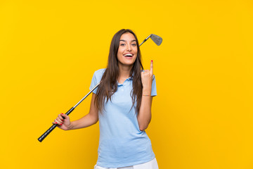 Young golfer woman over isolated yellow wall pointing up a great idea