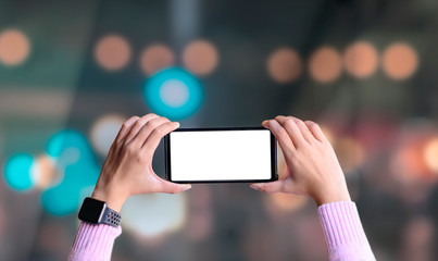 Wall Mural - Close-up of female hand holding horizontal blank screen smart phone with blurred bokeh background.