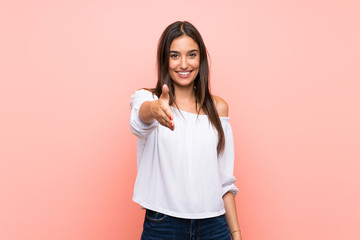 Young woman over isolated pink background shaking hands for closing a good deal