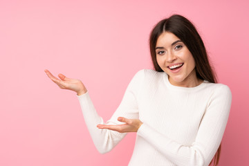 Wall Mural - Young woman over isolated pink background extending hands to the side for inviting to come