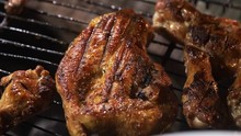 Closeup grilled chicken breast and wings on grill grate