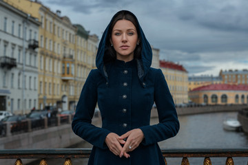 Poetic brown hair brunette sister beautiful woman girl vintage classic coat blue dress look camera green eyes hands together street old town outdoor blue sky river cars channel scenic city view