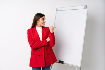 Young woman giving a presentation on white board pointing to the side to present a product