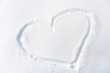 Heart drawn on fresh snow texture. Symbol of heart on snowy surface closeup.