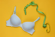 © splitov27 - Srylish women underwear bra and tape measure on yellow background. Breast loss concept, measuring bust. Top view