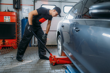 Wall Mural - Auto mechanic jacks the car in tire service