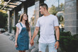 © GalakticDreamer - Positive male and female hipster guys holding each other on hands and walking around urban setting in city area,happy couple in love enjoying free time and summer vacations for flirting and recreating