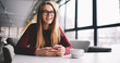 © GalakticDreamer - Smiling hipster girl in eyeglasses holding mobile phone in hand lauhhing at funny message , excited young woman chatting and checking notification about good news on smartphone connected to wifi
