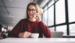 © GalakticDreamer - Clever skilled young female architect talking on cellular phone with colleague in break of work, beautiful successful woman smiling making call using app and new modern smartphone holding tea cup