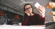 © GalakticDreamer - Thoughtfully female student holding mobile phone and taking selfie photos with front camera, young hipster girl sitting at cozy cafe table and using modern cellular for making video for new blog