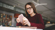 © GalakticDreamer - Young serious caucasian woman in eyeglasses checking banking balance via app on telephone, hipster girl holding smartphone in hand and typing text message using social network for chatting
