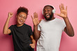 © wayhome.studio  - Staying alive and having fun together. Happy dark skinned millennial girlfriend and boyfriend feel relaxed, dance and listen songs in headphones, isolated over pink wall, clench fists and raise palms