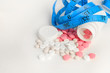 © daniiD - blister with tablets and tied with measuring tape, the concept of taking drugs for weight loss and maintain the figure, the harm of supplements for weight loss, isolated on white background