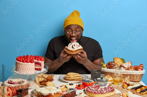Cuadros en Lienzo Happy celebrating sweet tooth man bites baked pancakes with cream, eats all dess