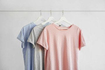 T-Shirts in pastel color on hanger on white background. Basic female clothes. Spring/summer outfit.