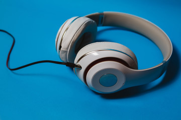 White audio headphones, isolated on blue background.