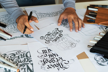 Wall Mural - Typography Calligraphy artist designer drawing sketch writes letting spelled pen brush ink paper table artwork.Workplace design studio.