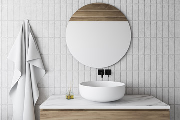 white tile bathroom with sink and round mirror