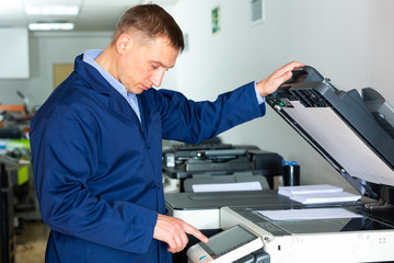 Portrait of confident service engineer standing by photocopy machine in office