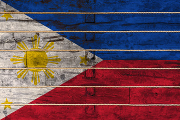 Wall Mural - National flag  of Philippines. on a wooden wall background. The concept of national pride and a symbol of the country. Flags painted on a wooden fence with a rope