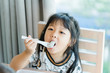 © MIA Studio - Little asian girl eating dragon fruit in restaurant,Cute toddler girl eating biting on dragon fruit.