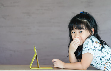 Wall Mural - Lovely little asian girl is applying the make up on her cheek with special brush on and looking mirror as she wants to look like her mother.Cute little girl playing with cosmetic at home.