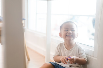 Baby asian boy playing hide and seek with funny moment under the table in kitchen, concept of learning by playing for child development.