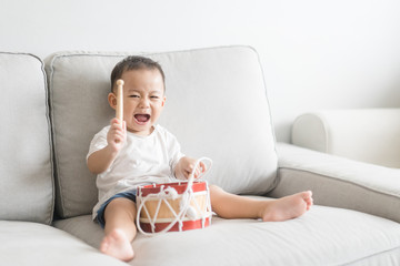 Wall Mural - Little baby drummer boy playing and hitting the drum set at home.Asian boy playing and singing happy moment in music lesson time.Child development and Executive function in child concept.