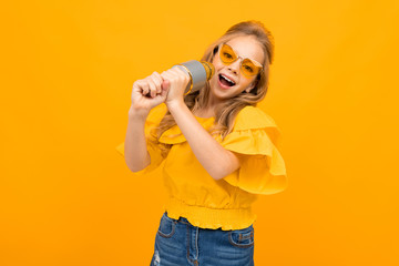 Wall Mural - Nice little girl with her glasses sings songs into the microphone isolated on white background