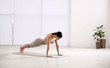 © New Africa - Young woman practicing plank asana in yoga studio. Phalankasana pose